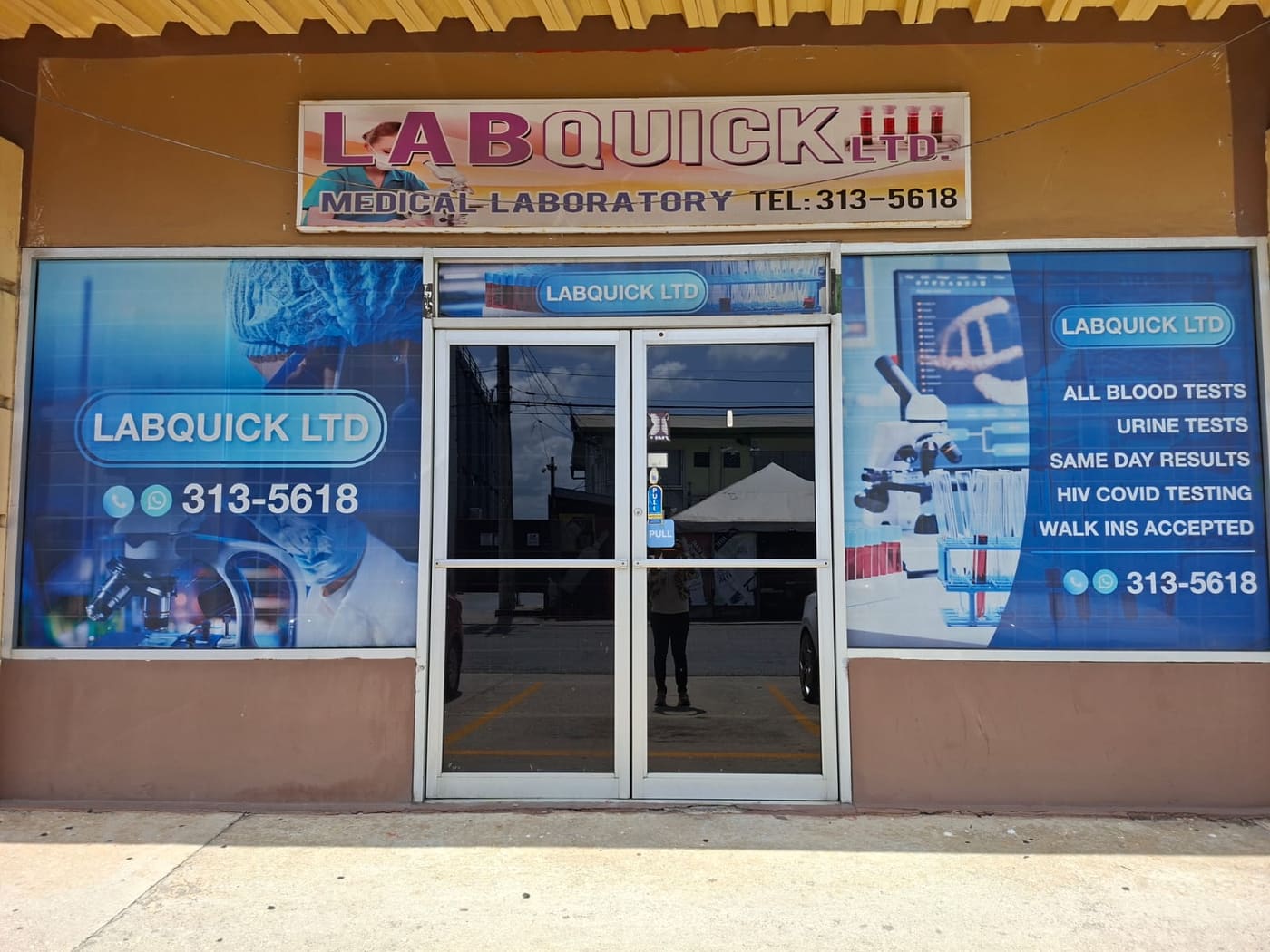 The front of the Labquick Ltd laboratory: a single-storey shopfront with a Labquick Ltd Medical Laboratory sign above glass double doors, flanked by windows printed with laboratory imagery.